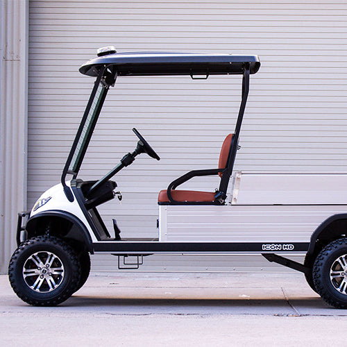White golf cart with black top and brown seat parked in front of a white garage door.