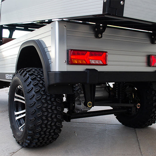 Close-up of a truck bed with a tail light and tire on a concrete surface