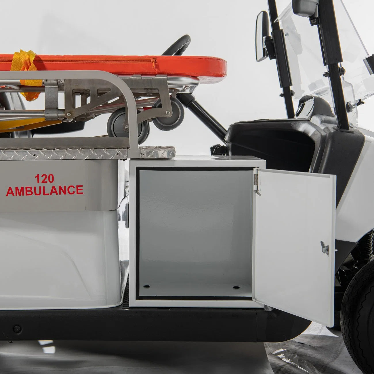 Ambulance interior with stretcher and open storage compartment.