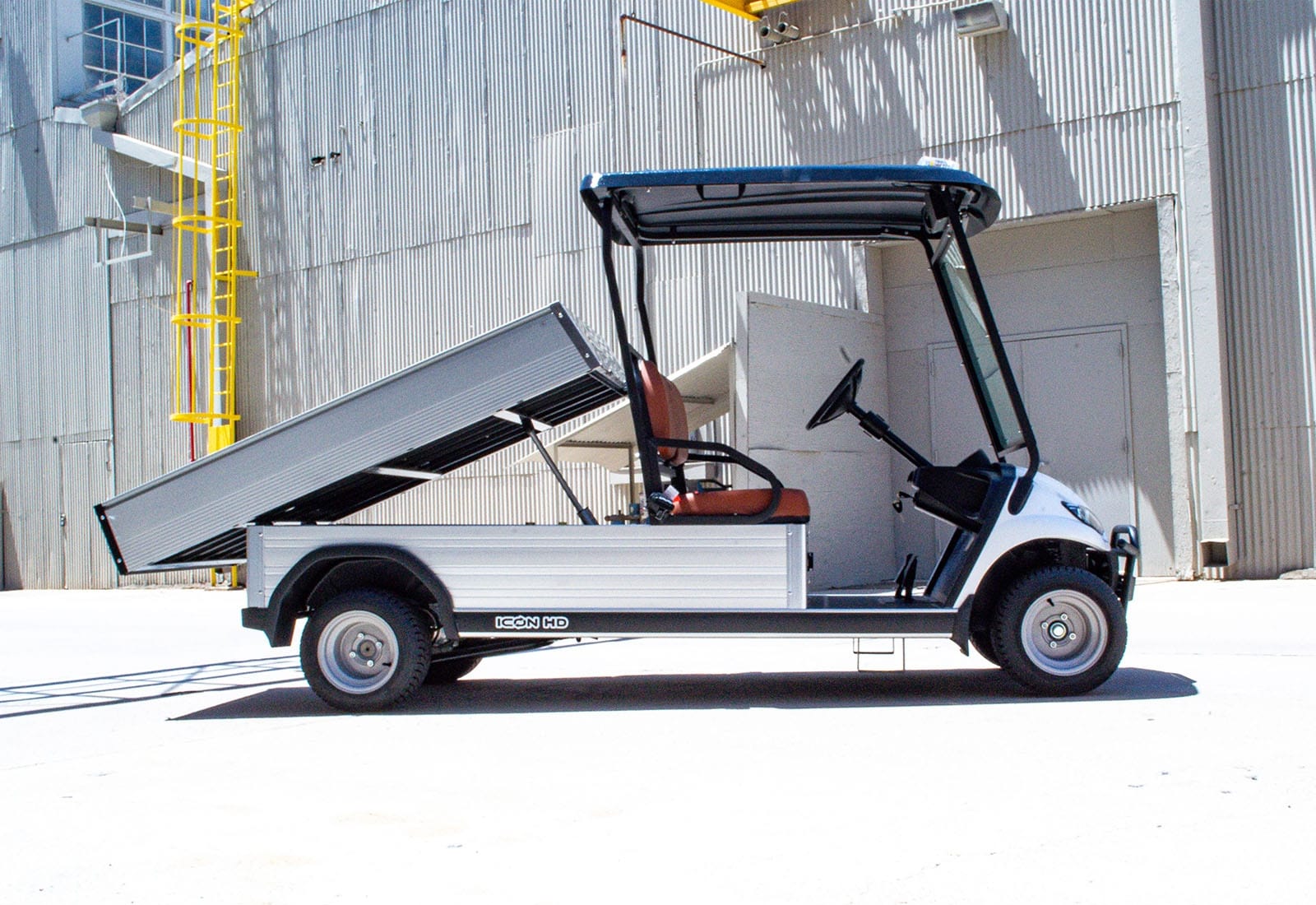 White utility vehicle with an open cargo bed in front of a building