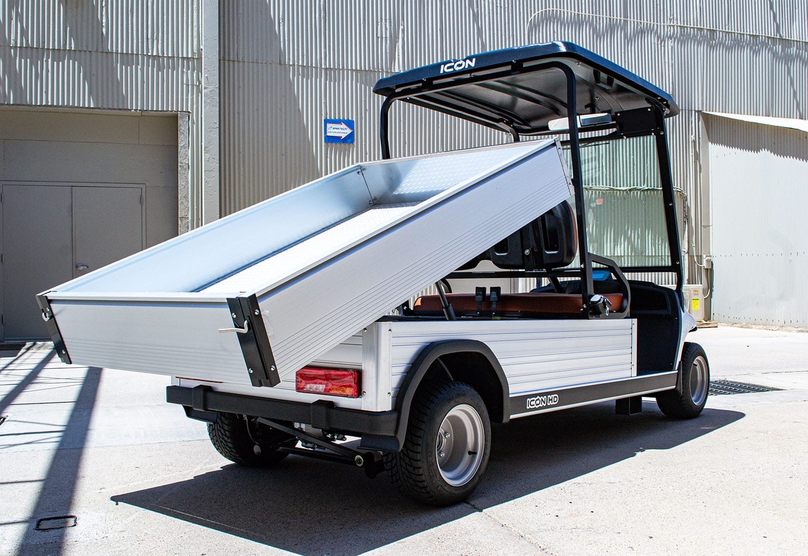 Utility vehicle with an open cargo bed on a concrete surface.