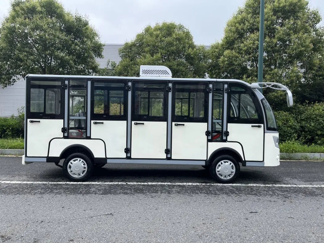 Small white bus on a road with trees in the background