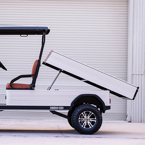 Golf cart with a trailer attached in front of a white garage door