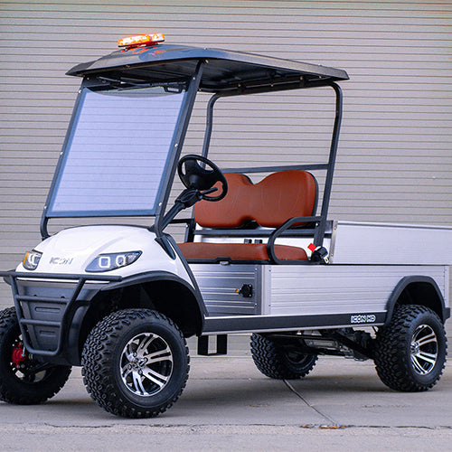 Golf cart with a cargo bed in front of a gray wall