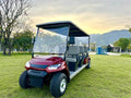 Red golf cart on a grassy area with trees and mountains in the background