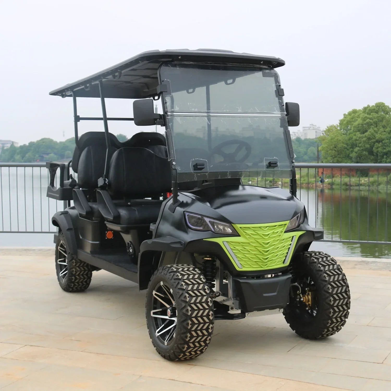 Black and green golf cart on a wooden deck with a lake and trees in the background