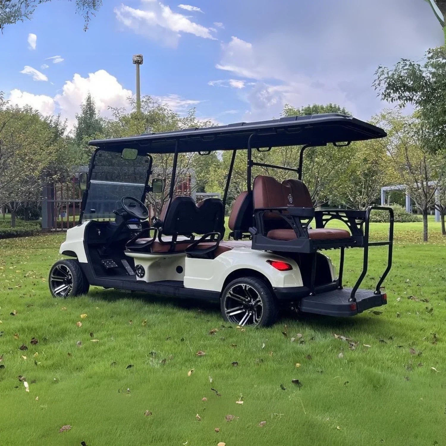 Golf cart on a grassy area with trees and clear sky in the background