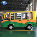 Small yellow and green bus inside a warehouse with a logo in the corner.
