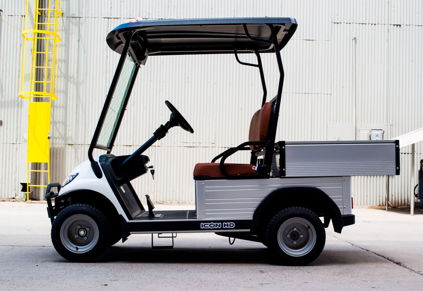 Golf cart with a tool box on a concrete surface against a gray wall.
