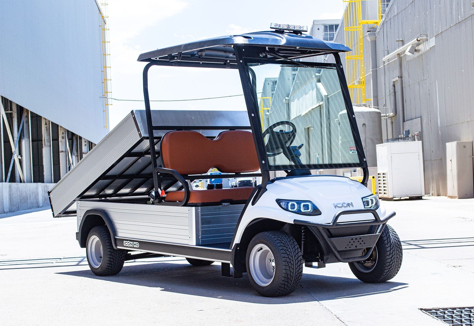 Electric golf cart with a cargo bed in an industrial setting