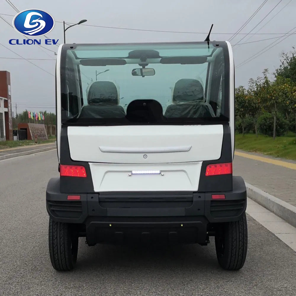 ocean cartz rear view of a white and black two-seater electric vehicle with a fully enclosed cab, parked on an asphalt street. This compact NEV or low-speed electric car features a large rear windshield, wraparound rear brake lights, a black bumper, and a horizontal white LED reverse light bar. The image highlights the modern, compact design of the neighborhood electric car.
