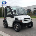 ocean cartz three-quarter front view of a white and black two-seater electric vehicle with a fully enclosed cab and a curved glass roof. This modern compact NEV or low-speed electric car is parked on an asphalt street, featuring black trim, a large windshield, and a small front grille. It is equipped with custom black and chrome alloy wheels, highlighting its use as an all-weather neighborhood electric car.