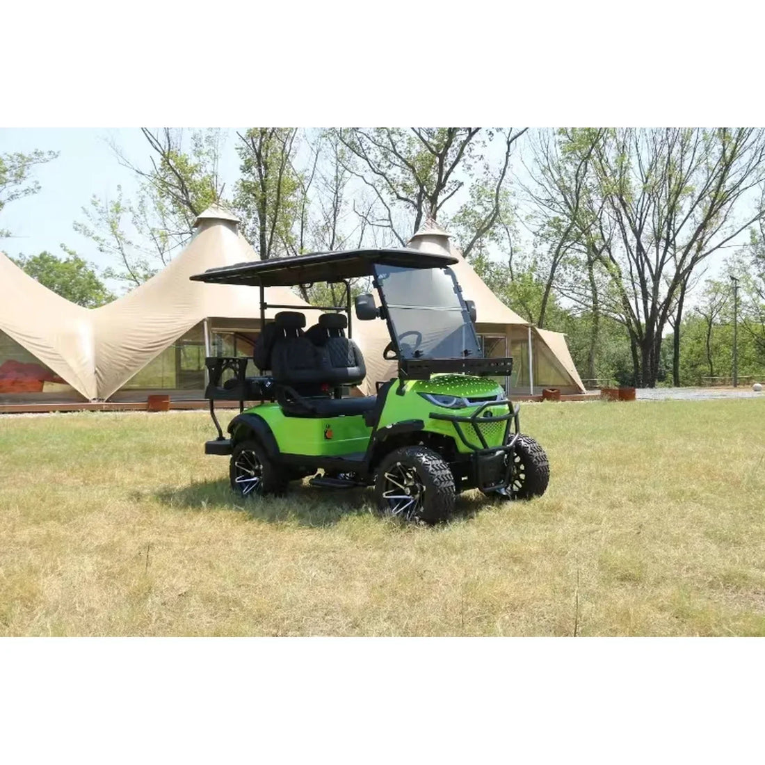 Green golf cart on grass with tents and trees in the background