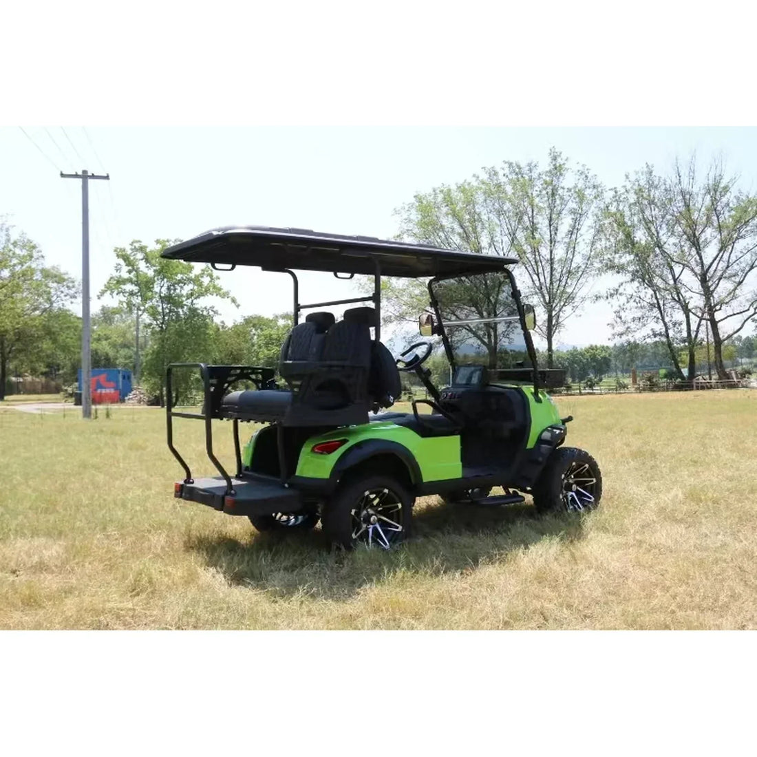 Green golf cart on grass with tents and trees in the background