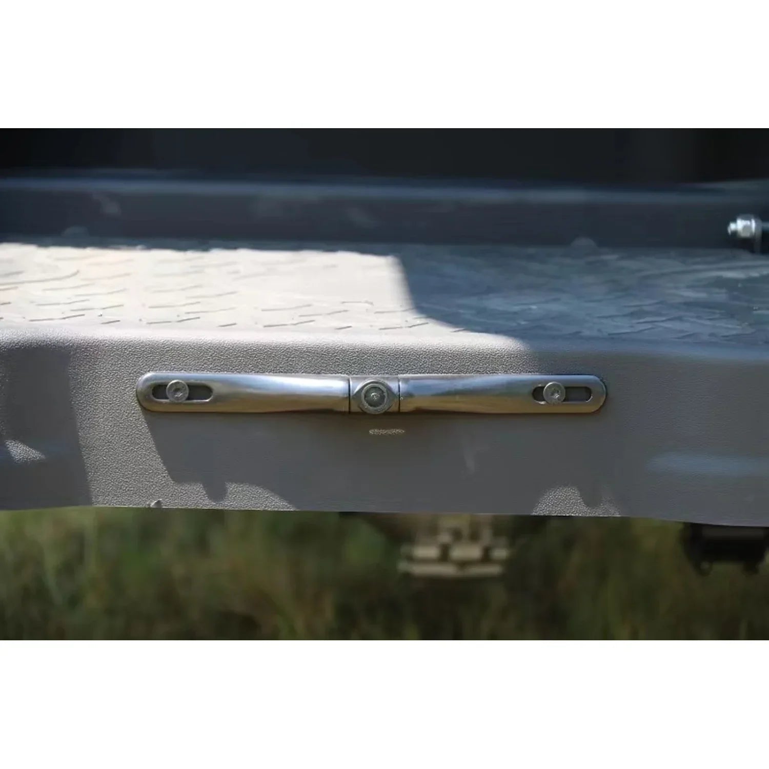 Metallic handle on a vehicle door with grass and pavement in the background