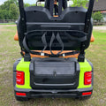 Back view of a green golf cart with open cargo area on grass