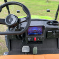 Golf cart interior with steering wheel and dashboard display on a grassy background