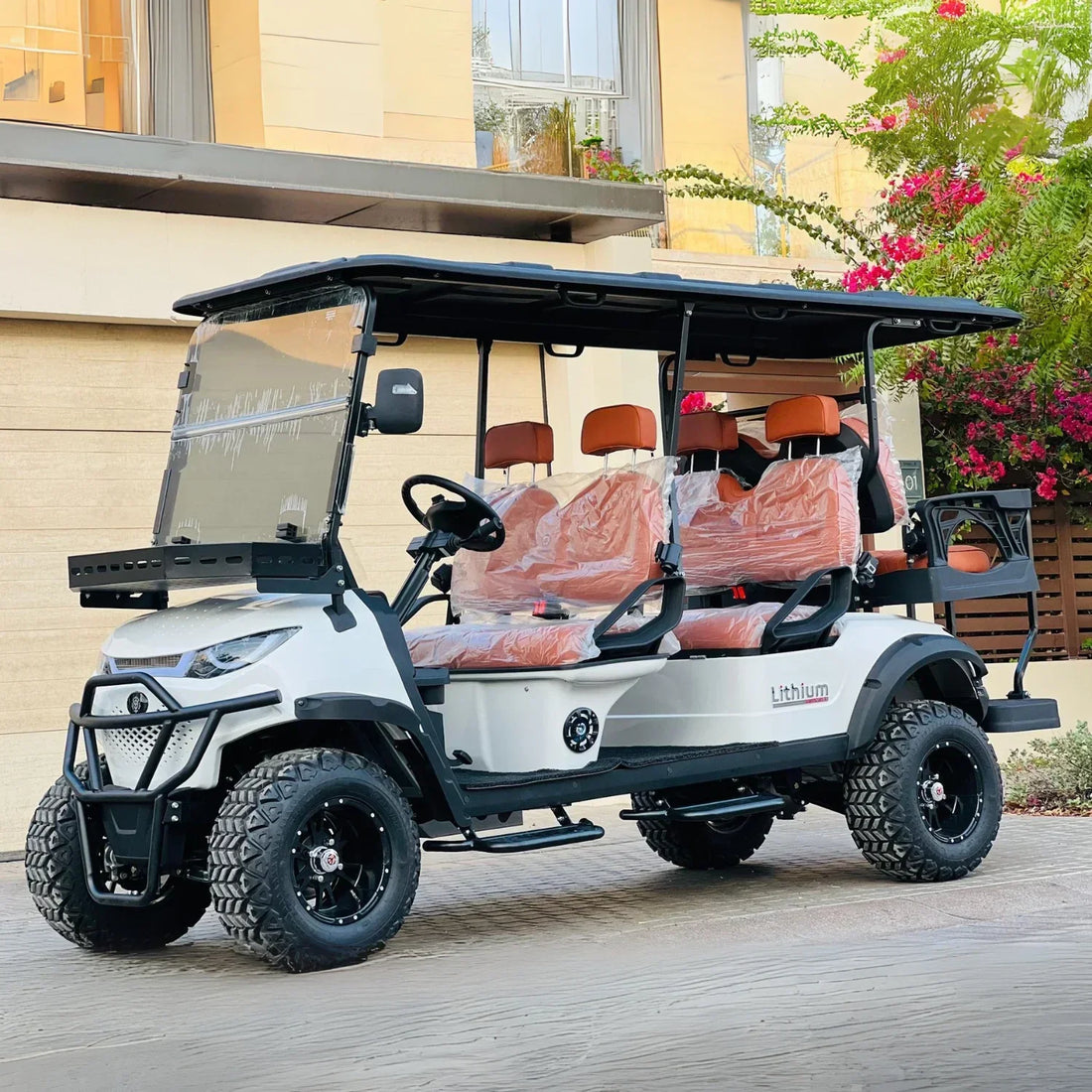 White golf cart with orange seats parked on a wooden deck.