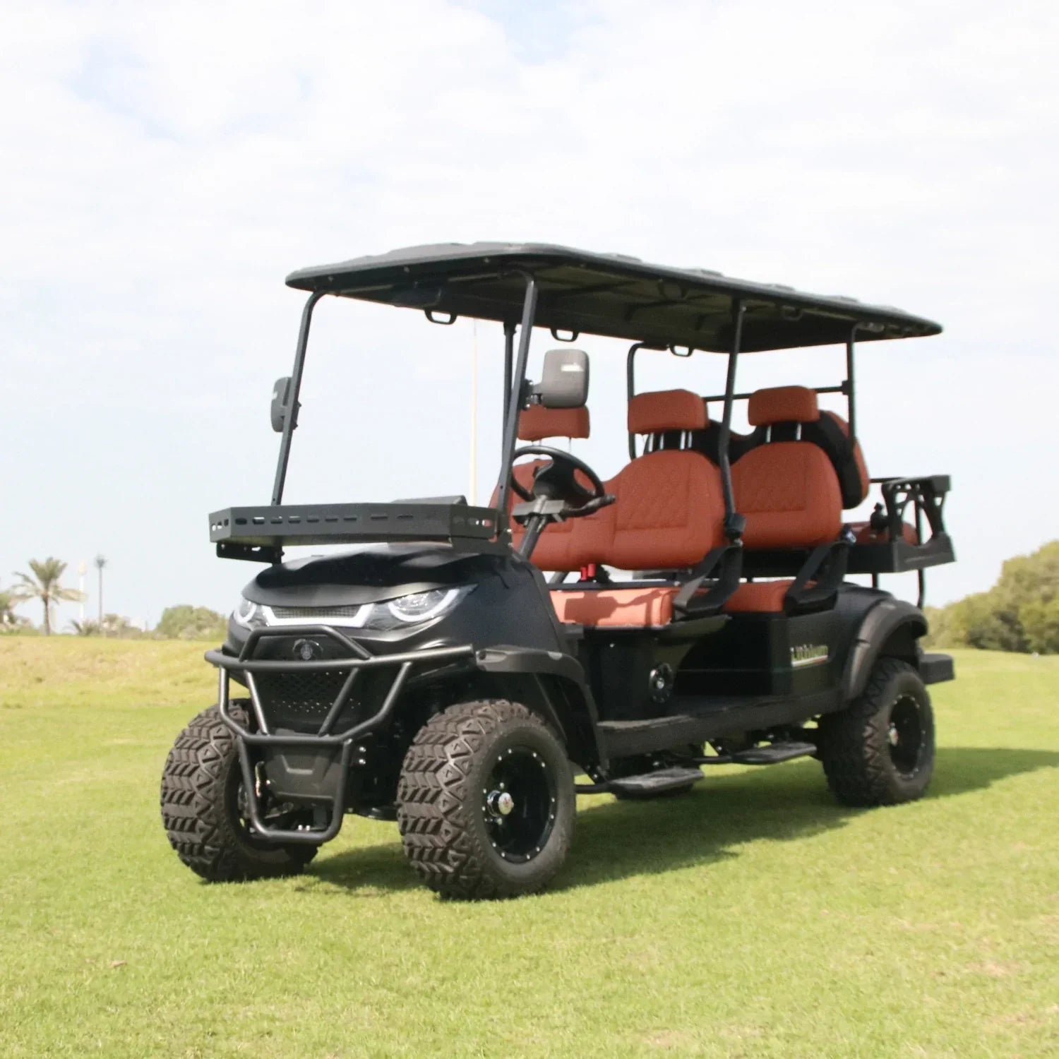 Black and red golf cart on a grassy field with trees in the background