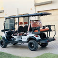 White golf cart with black roof and orange seats parked on a driveway.