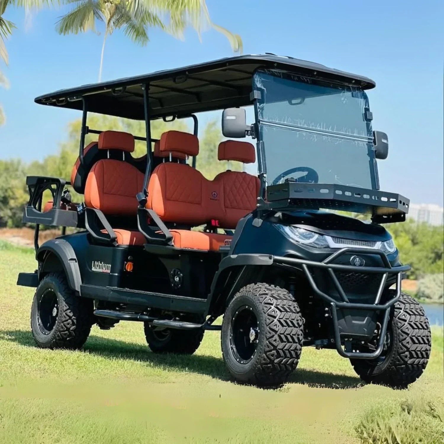 Golf cart with orange seats on a grassy area with palm trees in the background