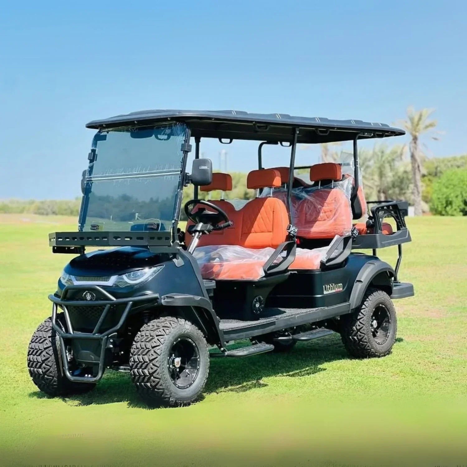 Golf cart with orange seats on a grassy field