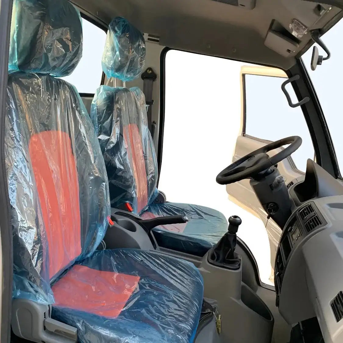 Red and black truck seats wrapped in clear plastic protective covers.