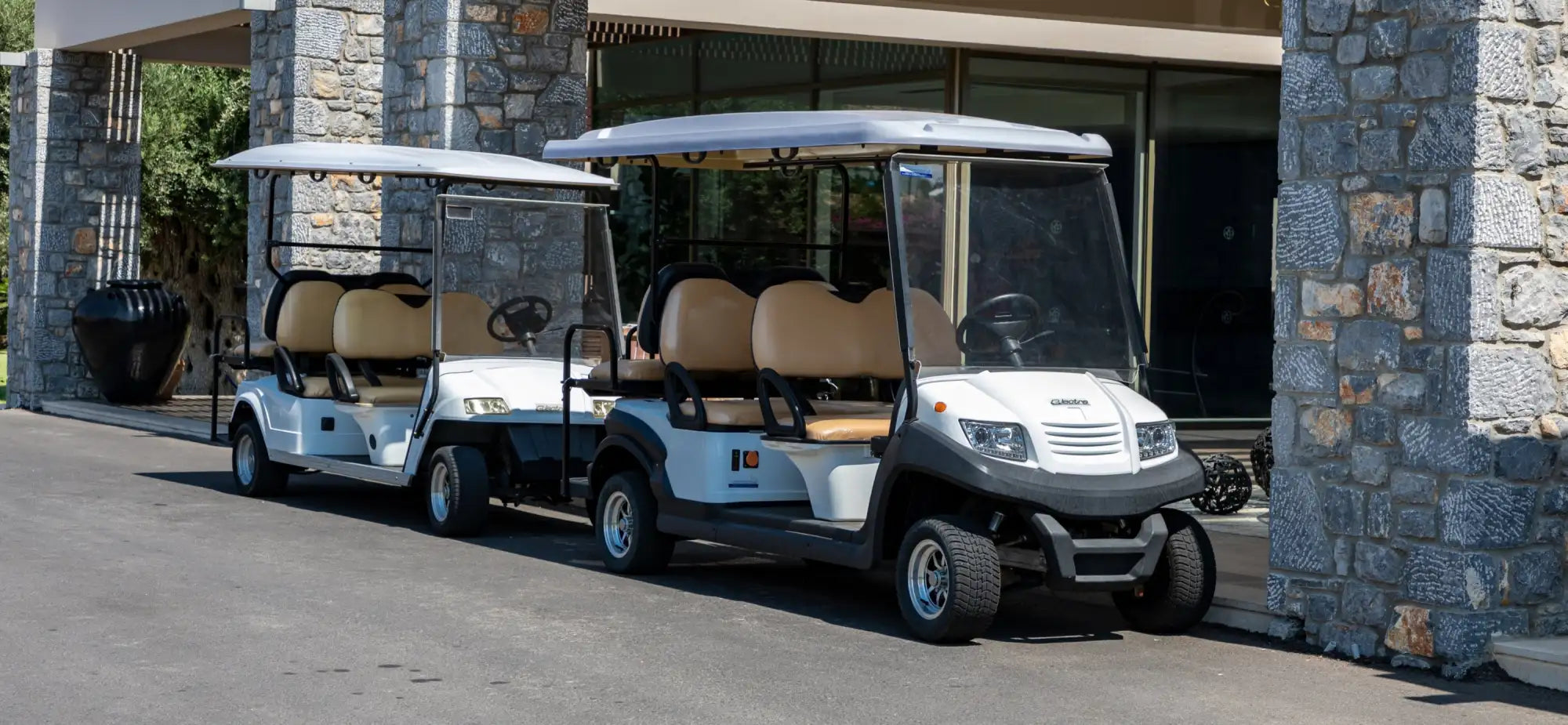 White and beige golf cart with a clear windshield, black front bumper, and tan seats.
